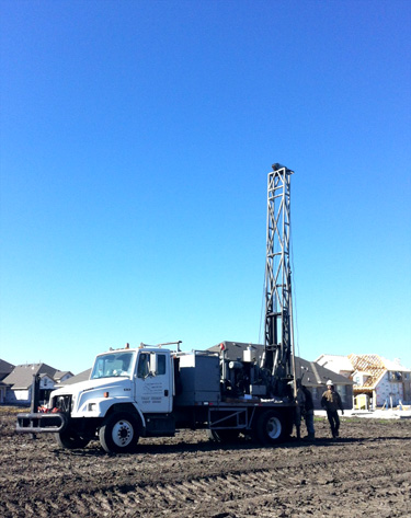 White Mobile B-59 drilling truck with metal drilling mast in residential development area